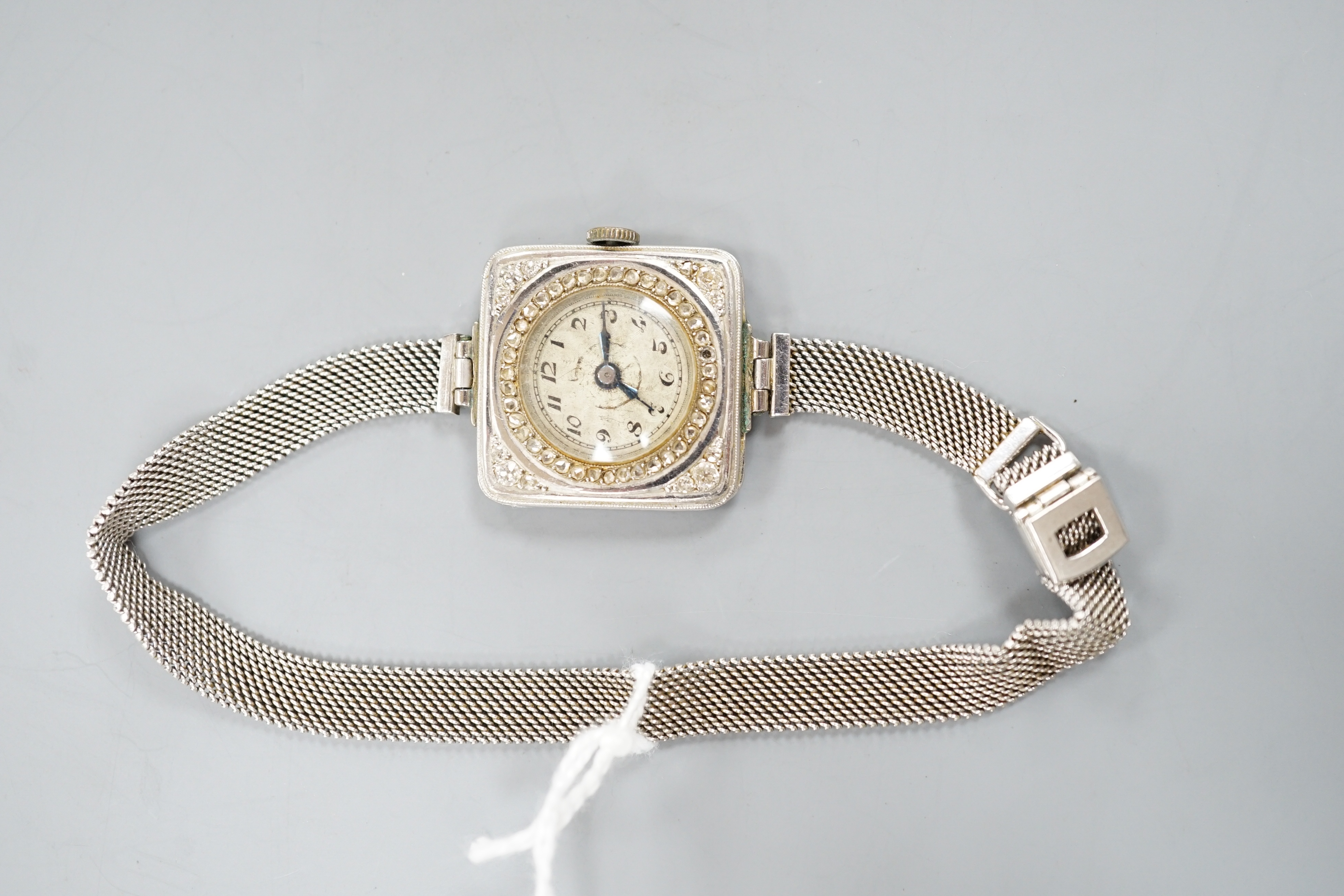 A lady's early 20th century white metal (stamped Plat) and diamond chip set manual wind cocktail watch, on a later 9ct white gold mesh link bracelet, gross 26.3 grams, (stone missing).